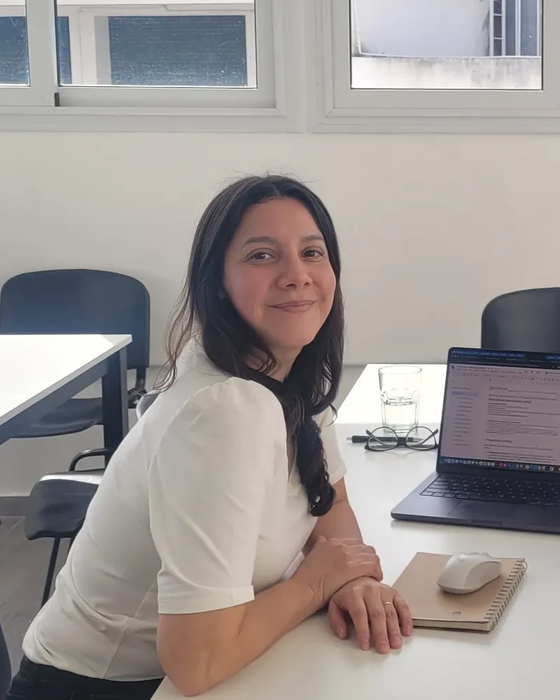 Luz Guillén sonriendo en su espacio de trabajo, junto a su notebook